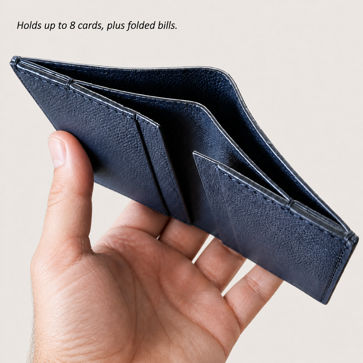 Hand holding an open navy Tyrian Minimal Wallet with card and bill compartments
