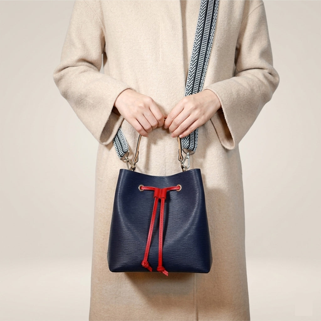 Navy Dorothy Bag held by the leather top handle with patterned webbing strap