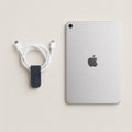 Cord Wrap in Dark Navy German Togo leather beside a charging cable and tablet.