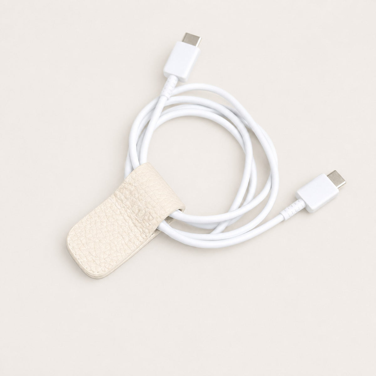 Charging cable secured with an Eggshell German Togo leather Cord Wrap.